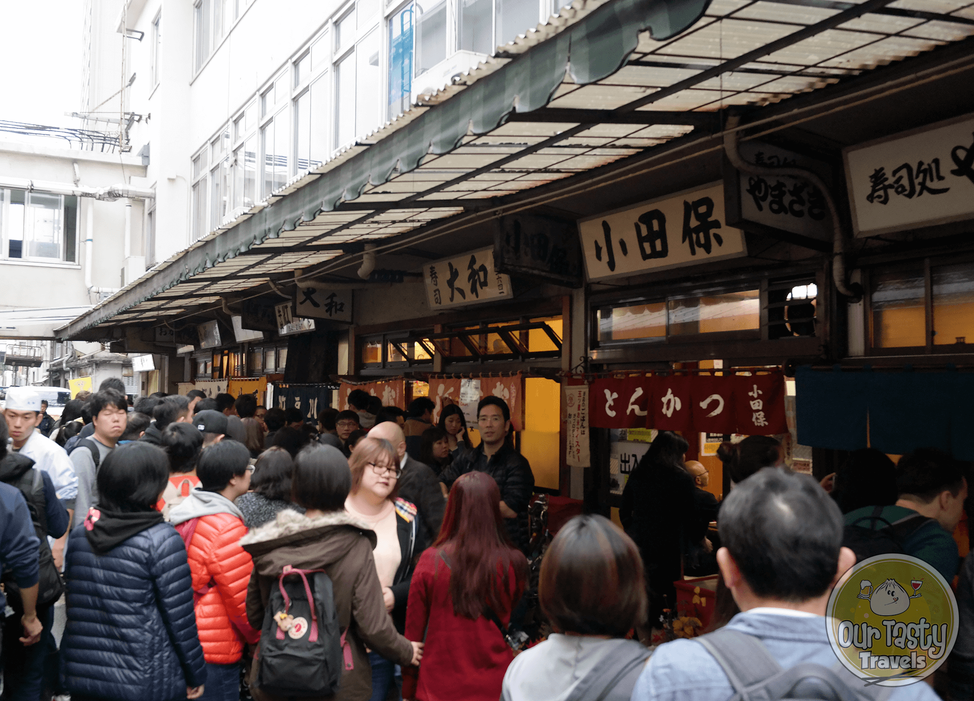 The line of people waiting to get in to try Daiwa Sushi at the Tsukiji Fish Market in Tokyo, Japan - ourtastytravels.com